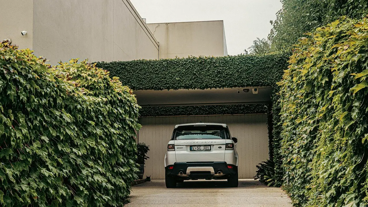 Concrete driveway leading to a garage between hedges