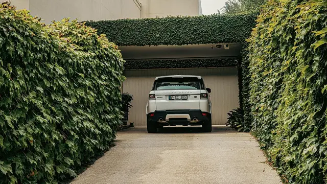 Concrete driveway leading to a garage between hedges