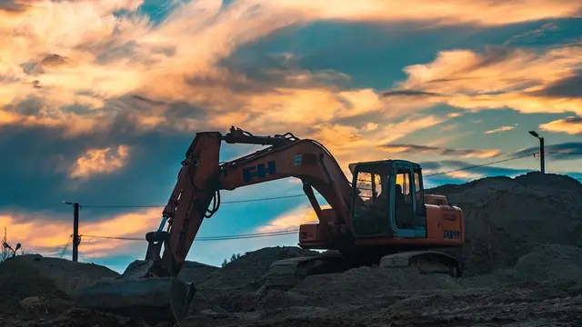An excavator digging at sunset