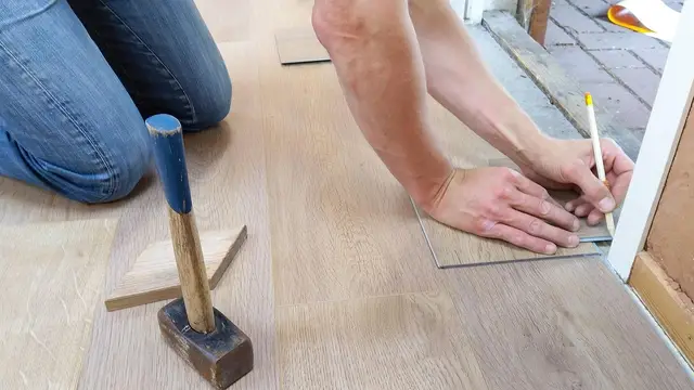 Hands fitting new laminate floorboards