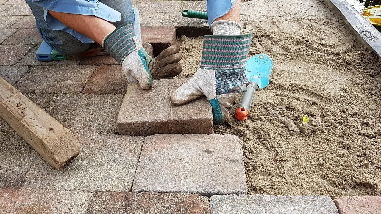 Hands setting paving stones in sand