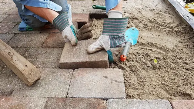 Hands setting paving stones in sand
