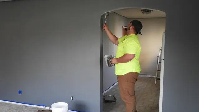 A painter rolling a fresh coat onto an interior wall