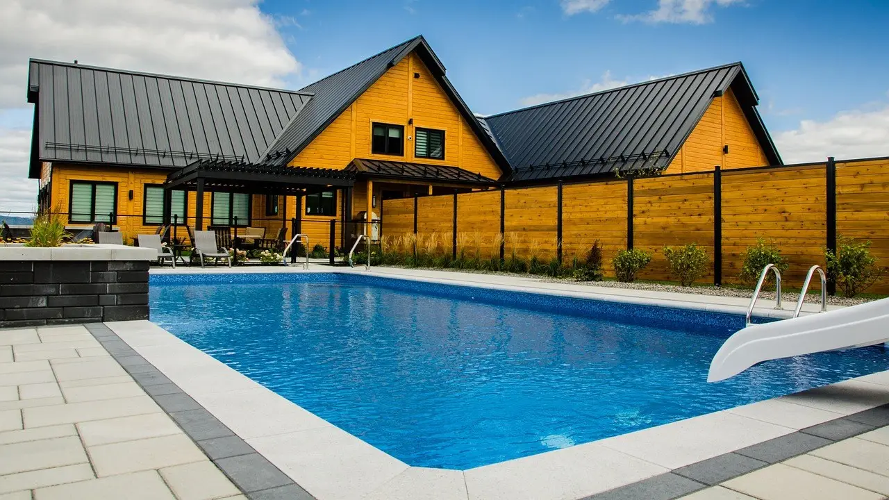 Backyard inground pool next to a house with a slide