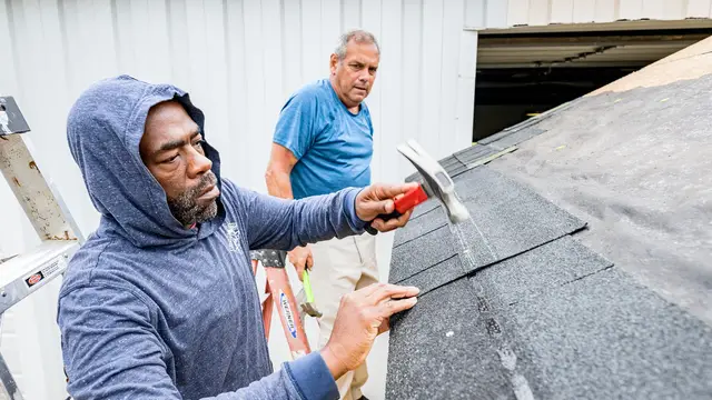 Hands fitting a shingle during roofing work