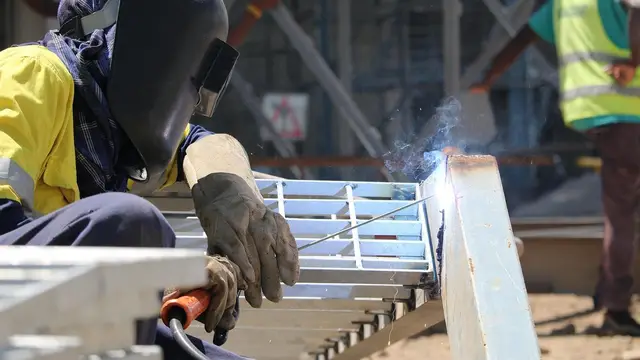 A welder in a mask welding steel